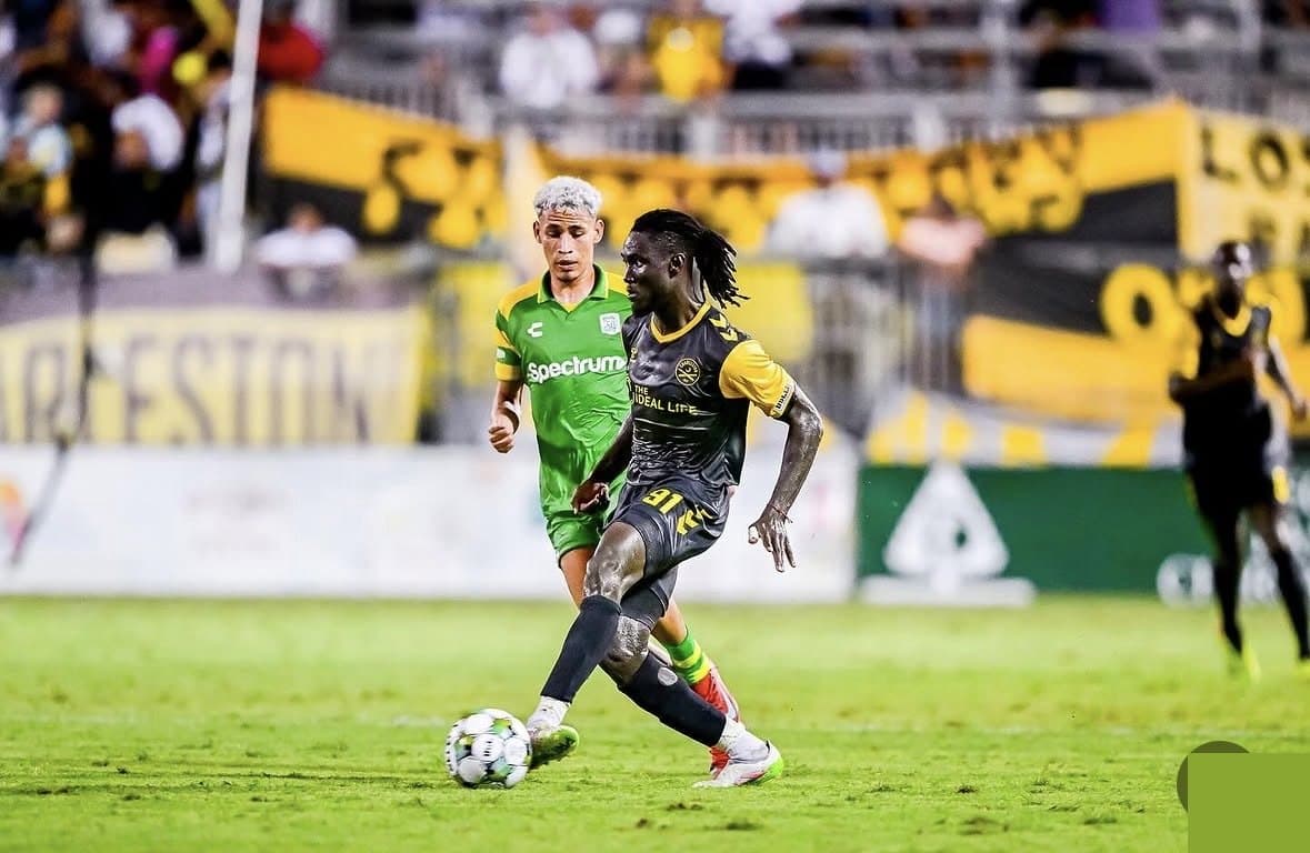 A Charleston Battery player in match action under stadium lights